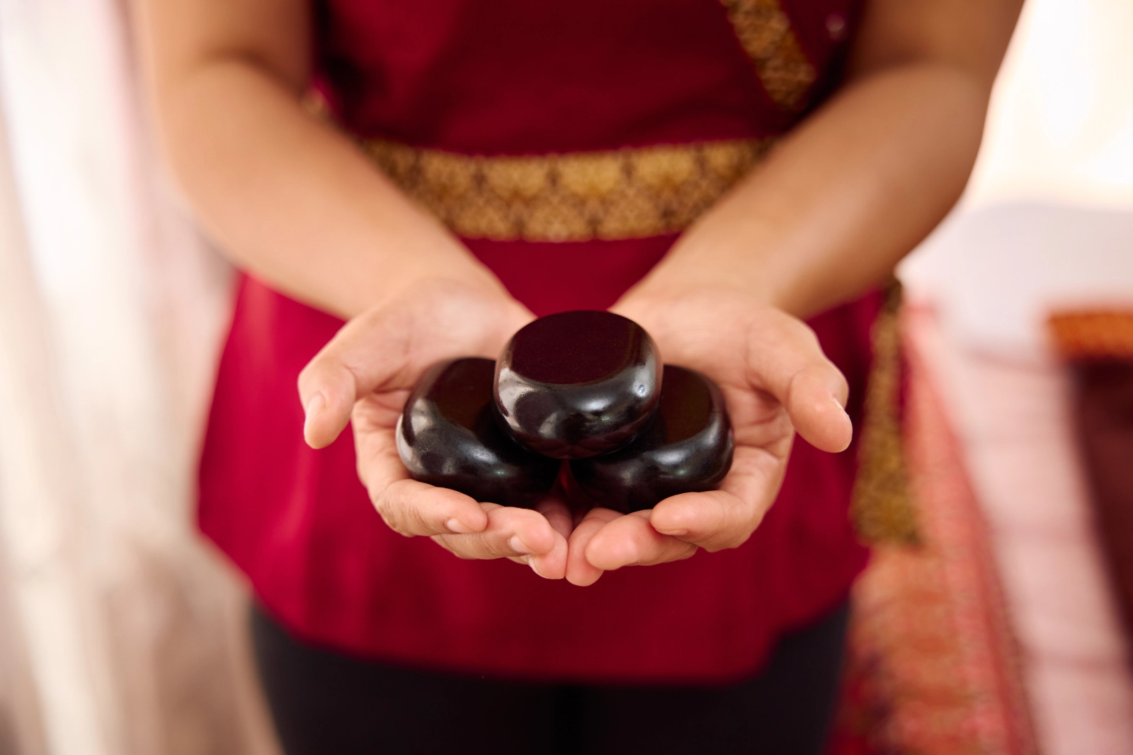 3 Massagesteine in offenen Händen für die Hot Stone Massage